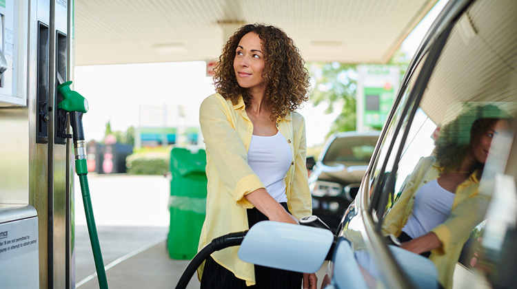 Junge Frau an betankt ihr Auto an der Tankstelle