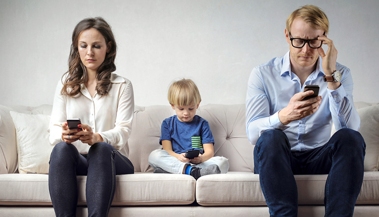 Eltern mit Kind auf Sofa, alle mit Smartphone
