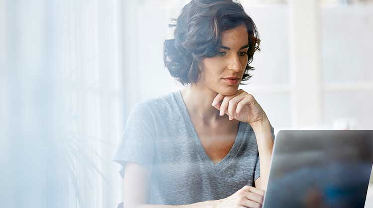 Junge Frau sitzt konzentriert vor ihrem Laptop