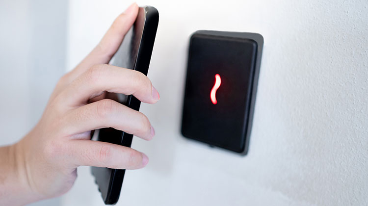 Hand mit Smartphone identifiziert sich für die Zutrittskontrolle in einem Gebäude