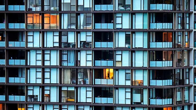 Fassade eines Wohnblocks mit teilweise erleuchteten Fenstern