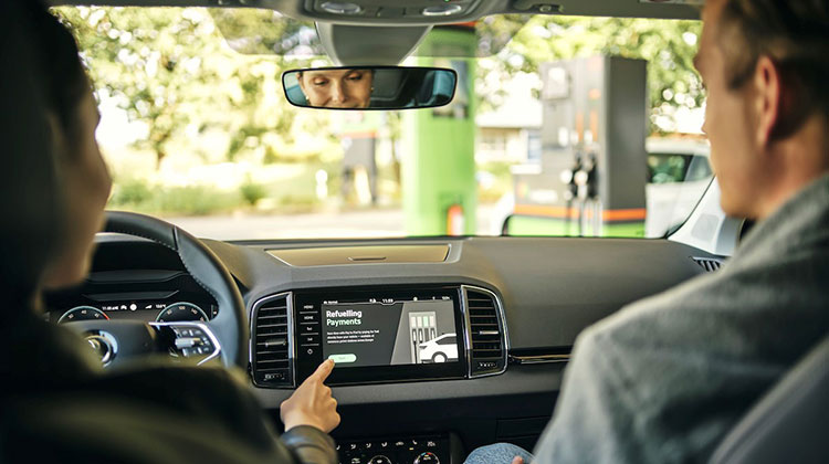 Eine Dame bedient in ihrem Auto über den Monitor das In-Car-Payment