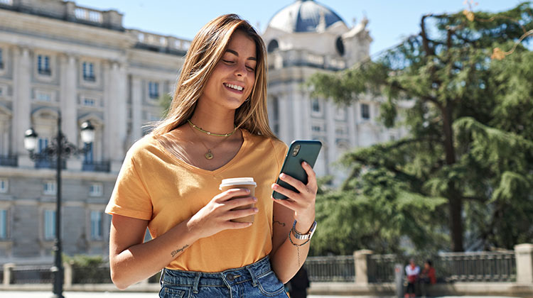 Junge Frau im Urlaub, die ihr Handy checkt