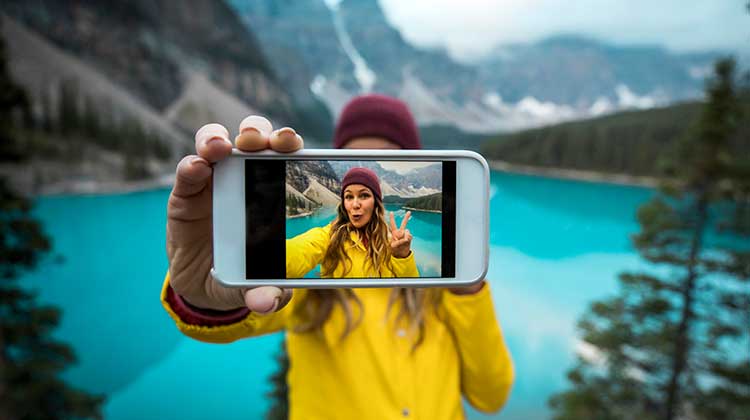 Junge Frau macht in den Bergen ein Selfie mit ihrem iPhone