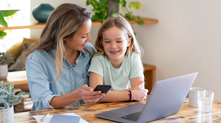 Eine junge Mutter mit Smartphone zeigt ihrer Tochter, wie ihr Portfolio funktioniert