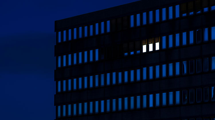 Bürogebäude im Dunkeln mit nur drei erleuchteten Fenster