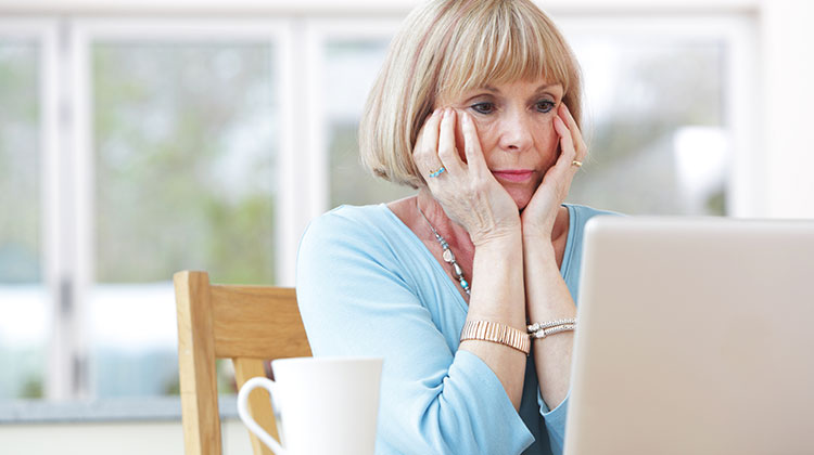 Rentnerin blickt besorgt auf ihren Laptop