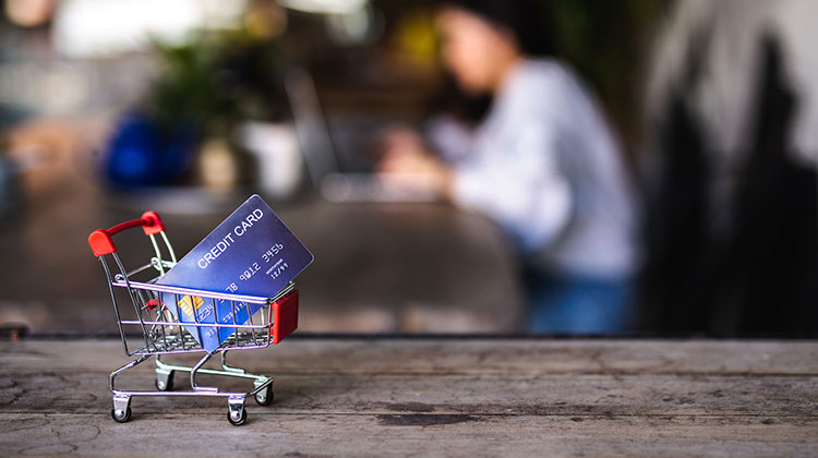 Miniatur-Einkaufswagen mit Kreditkarte auf einem Tisch