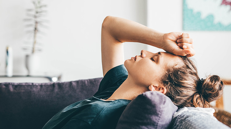 Junge Frau auf dem Sofa, die sich Sorgen macht und sichtbar Depressionen hat