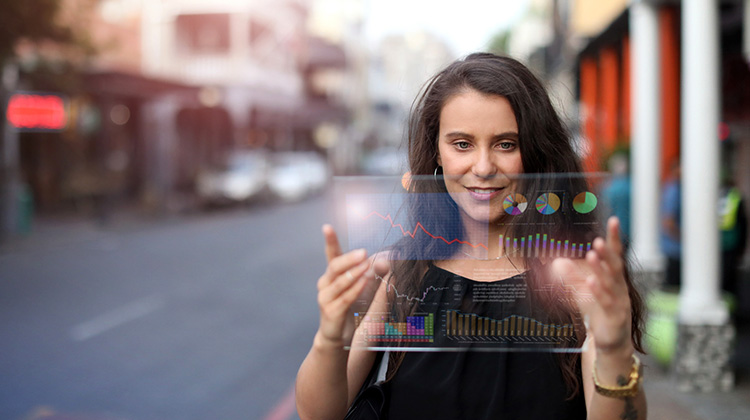 Eine junge Frau schaut auf einem Tablet auf der Strasse ihre digitalen Assets an