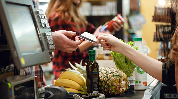 Eine Frau zahlt an der Ladenkasse mit Debitkarte