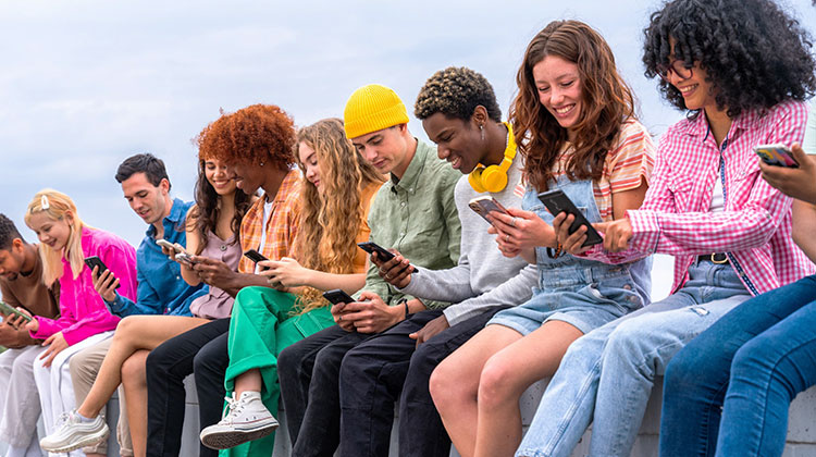 Viele junge Menschen nebeneinander, alle lachen und sind mit ihrem Smartphone beschäftig