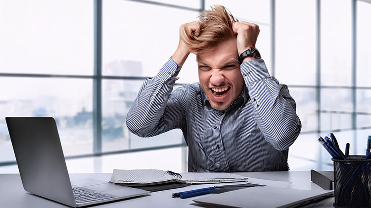 Junger Mann im Büro rauft sich verzweifelt die Haare