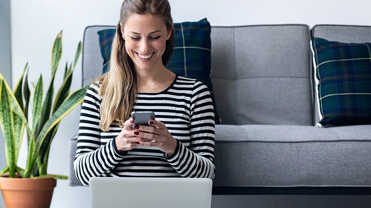 Junge Frau zu Hause am Smartphone und Laptop
