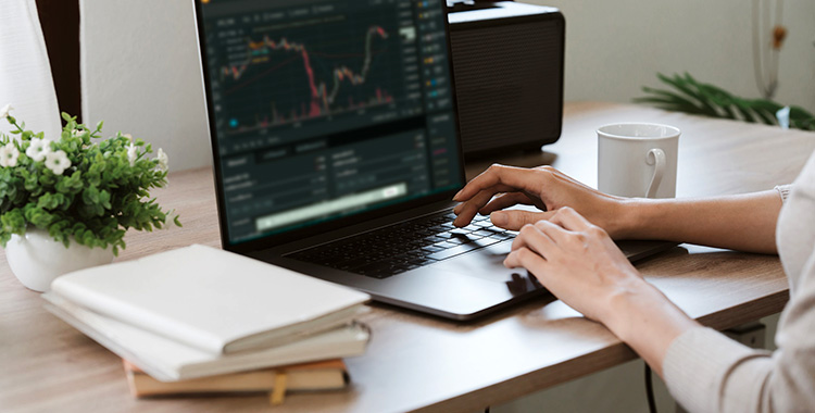 Junge Frau am Laptop beim Traden von Kryptowährungen