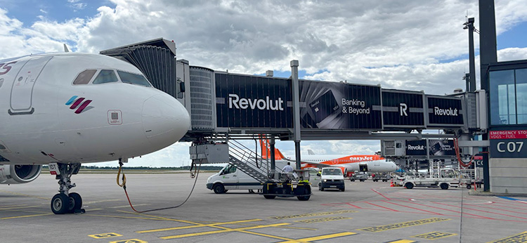 Fluggastbrücke zum Flugzeug mit Werbung der Challenger-Bank Revolut