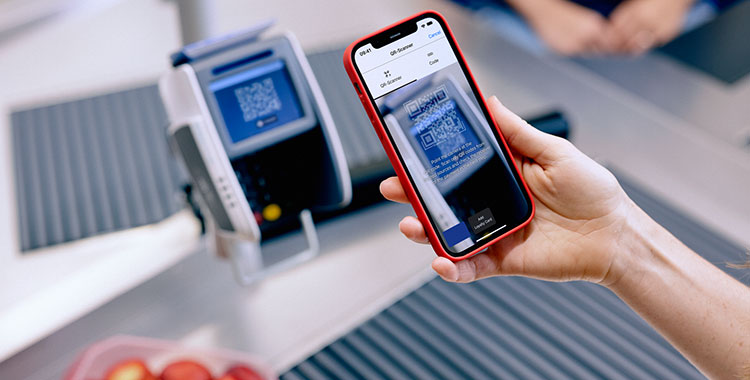 Frau mit Smartphone bezahlt an der Ladenkasse mit Twint