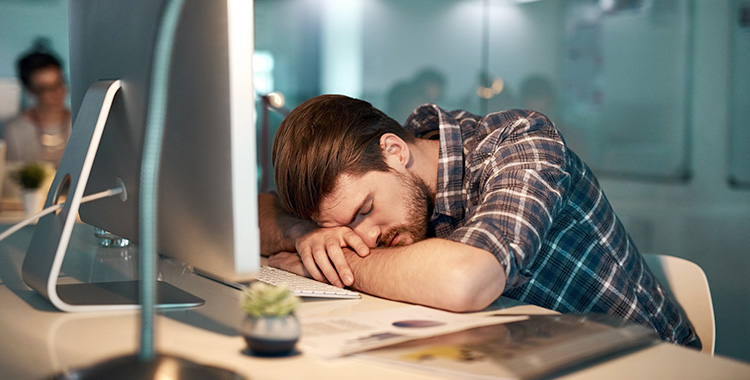Ein schlafender Mitarbeiter am PC zeigt AI-Fatigue