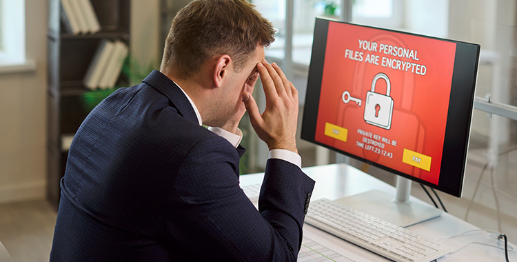 Geschäftsmann vor Monitor mit dem Hinweis, dass sein PC gehackt wurde