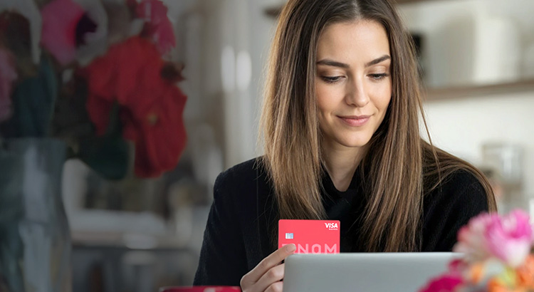 Junge Unternehmerein am Laptop mit Kreditkarte in der Hand