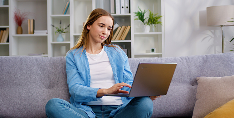 Junge Frau auf Sofa am Laptop
