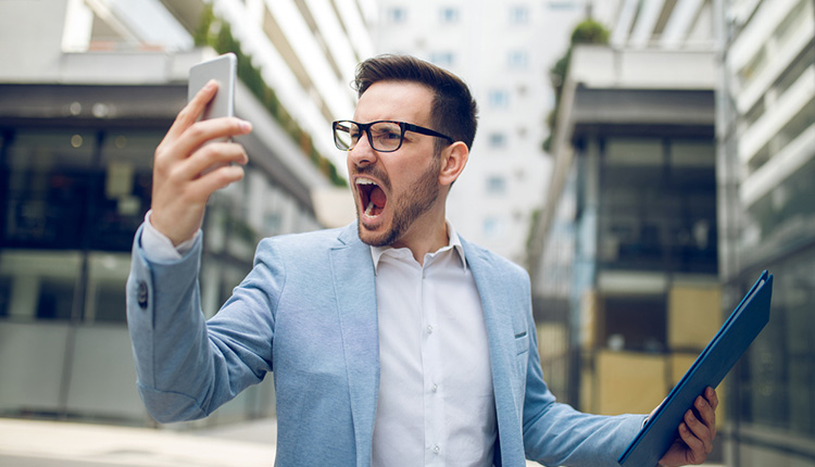 Junger Mann mit Smartphone ärgert sich