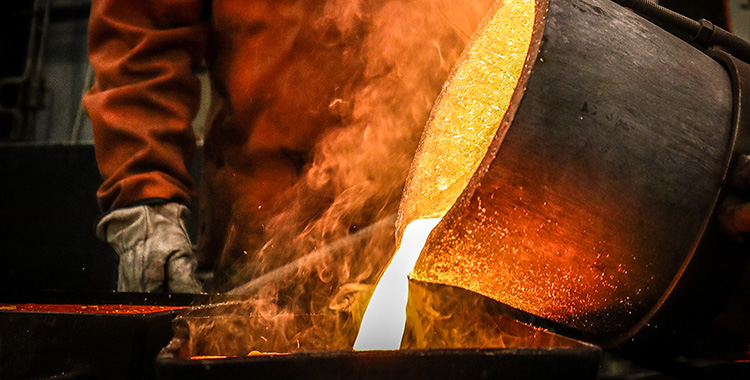 Ein Arbeiter lässt geschmolzenes Gold in einen Kübel fliessen