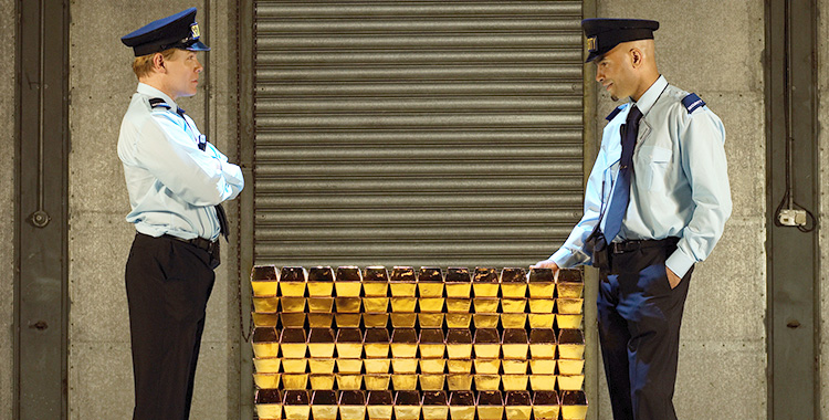 Zwei Wachleute vor einem Palett mit Goldbarren in einer Zentralbank