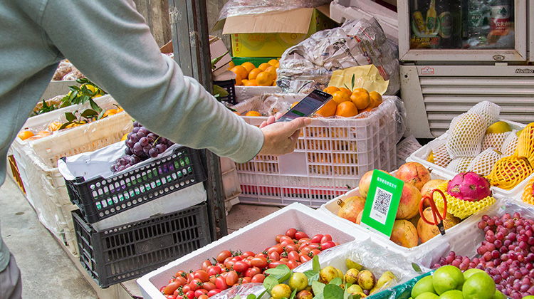 Mobile Zahlung mit WeChat, Hand mit Smartphone scannt einen QR-Code auf dem Markt